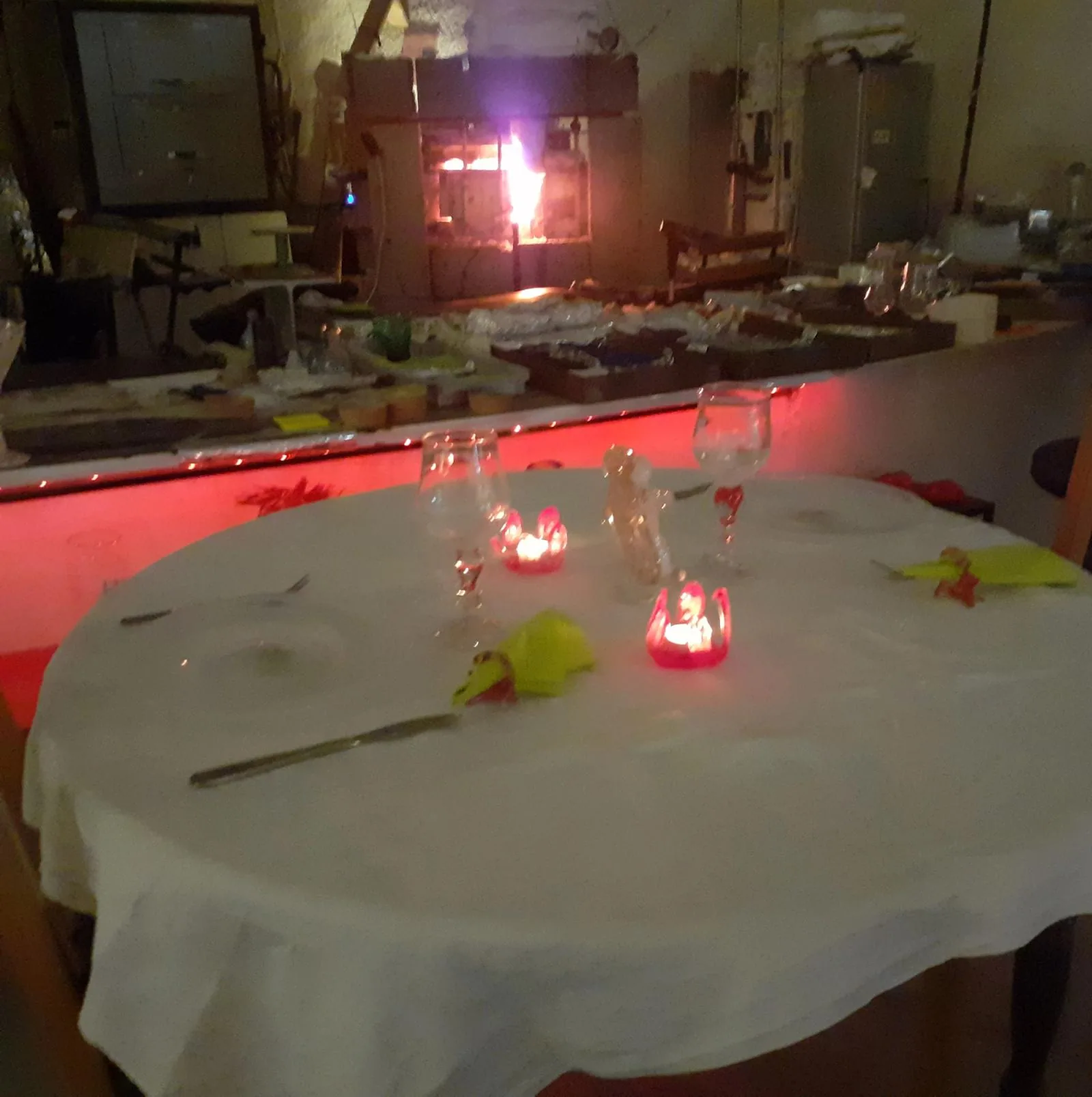 Dukat bord med egenblåsta glas och levande ljus framför glasugnen
